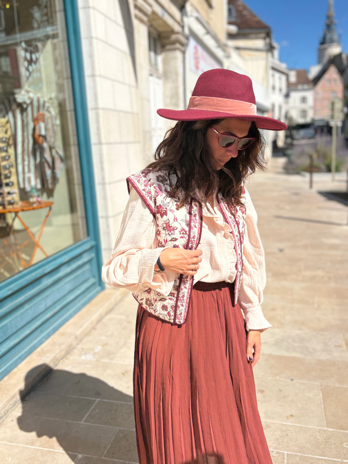 Jupe ANAÏS porté avec une blouse et un gilet à fleurs. Look automnal accessorisé d'un chapeau et de lunettes. Disponible au cerf volant auxerre.