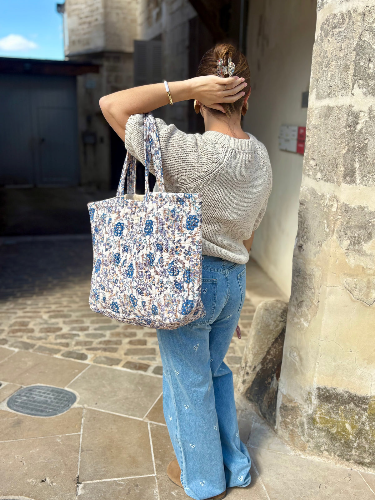 Jean flare et pull en maille manches courtes, avec un cabas fleuri. Disponible au cerf volant auxerre