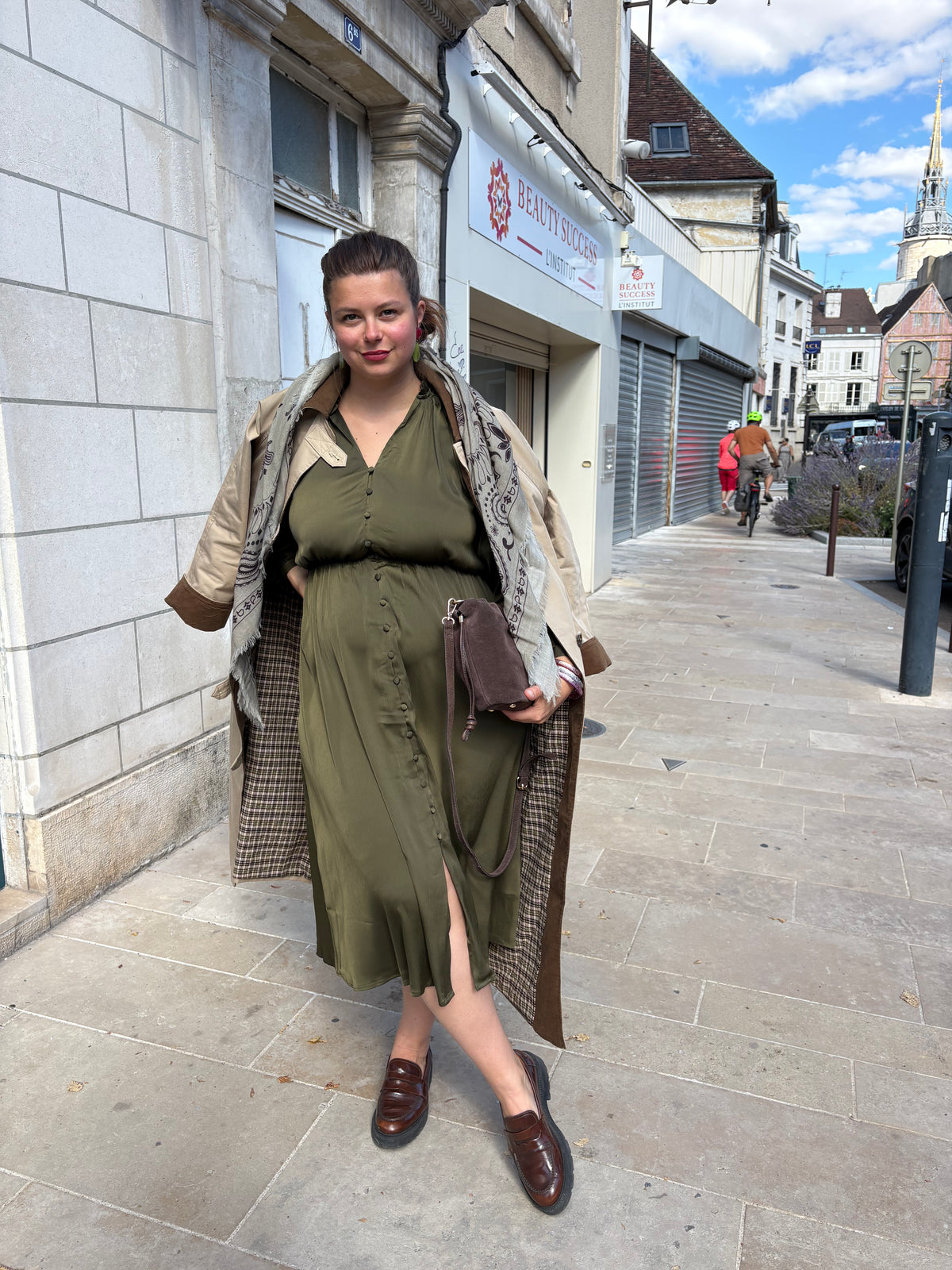 robe fluide col volanté kaki, porté avec un trench camel et un sac seau disponibles chez au cerf volant